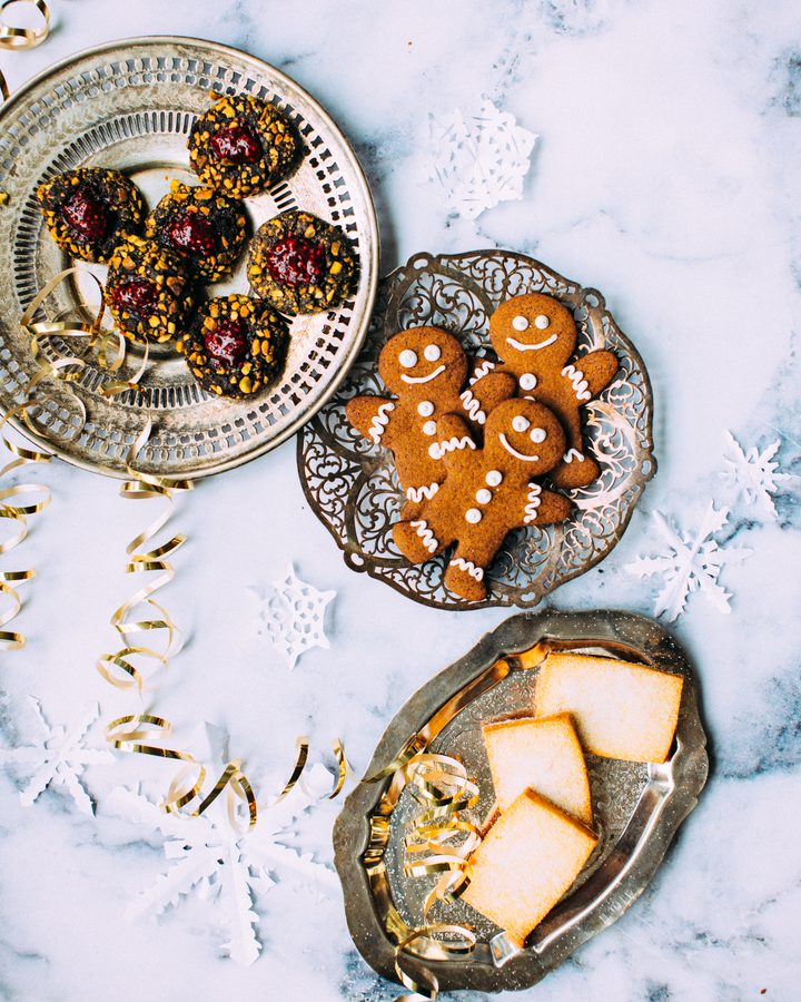 Biscoitos de gengibre em formato de bonequinhos e docinhos natalinos em bandejas decoradas