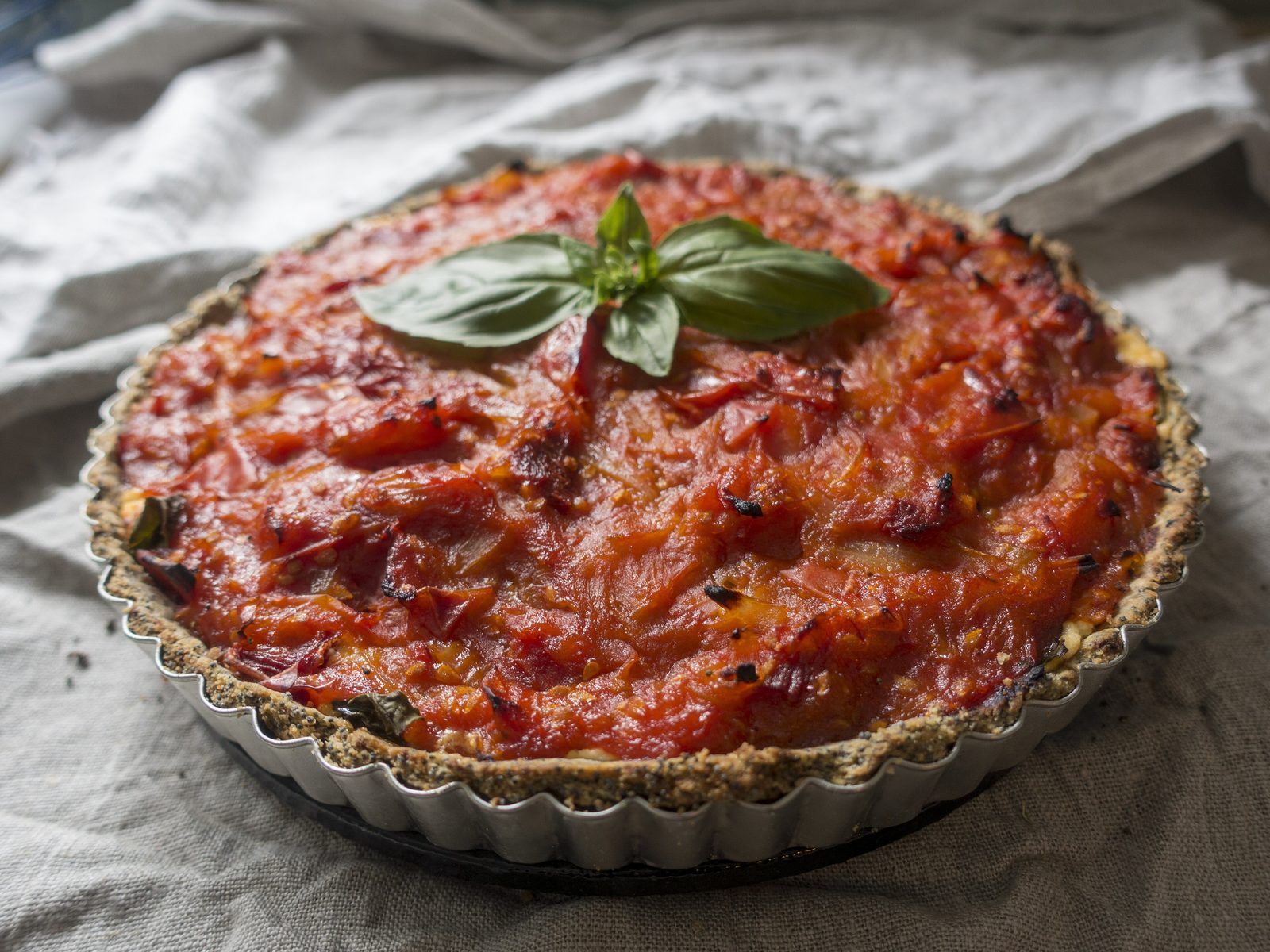 Torta salgada de tomate finalizada com folhas de manjericão