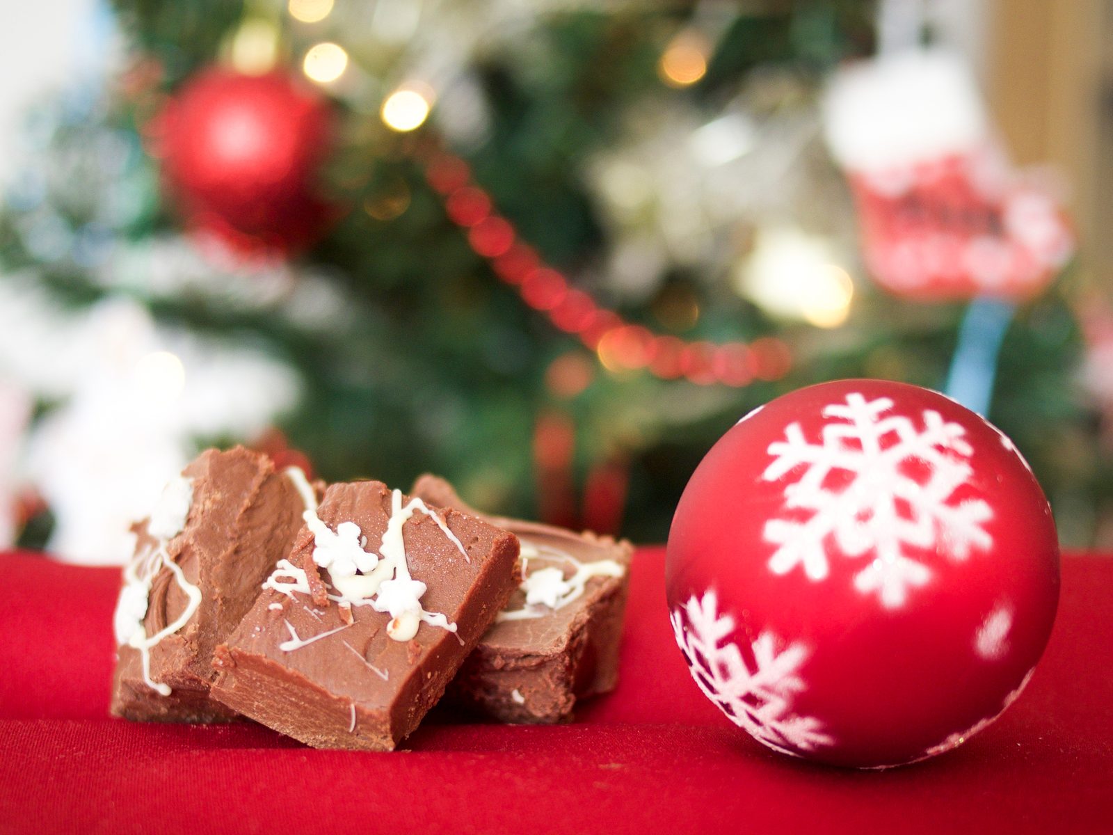 Brownies com cobertura de chocolate branco ao lado de uma bola de Natal vermelha
