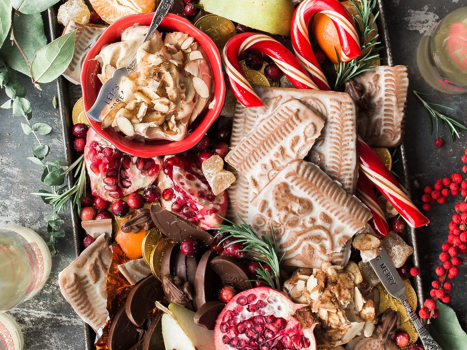 Tábua festiva com biscoitos, bengalinhas doces, romã, castanhas e chocolates